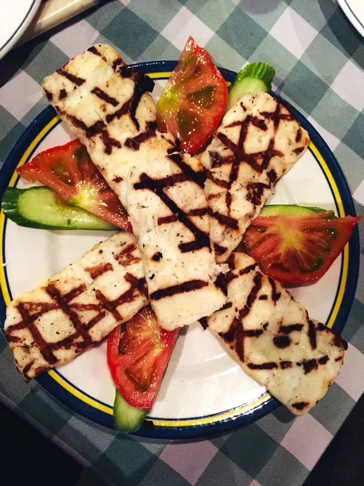Grilled halloumi, tomatoes and cucumber on a green checked tablecloth